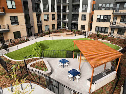 A patio with a table and chairs is surrounded by a black fence.