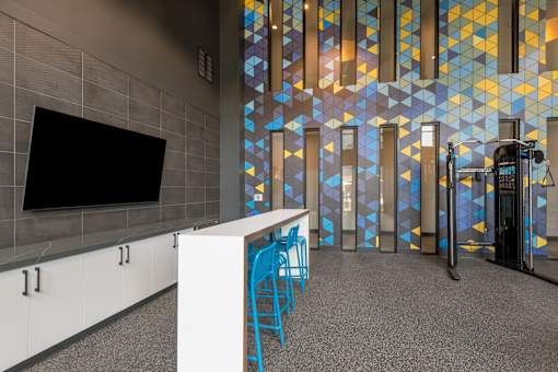 A room with a white counter and blue chairs.