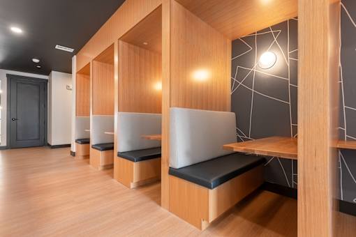 A row of wooden benches with black cushions are lined up in a room.