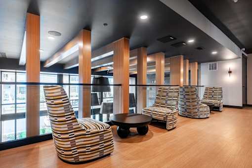 A row of striped chairs are lined up in a room with wooden floors and a large window.