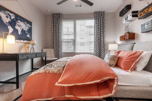 A bedroom with a bed covered in an orange duvet.