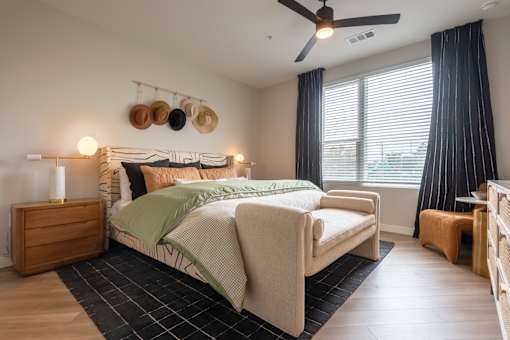 A bedroom with a bed, a nightstand, and a ceiling fan.