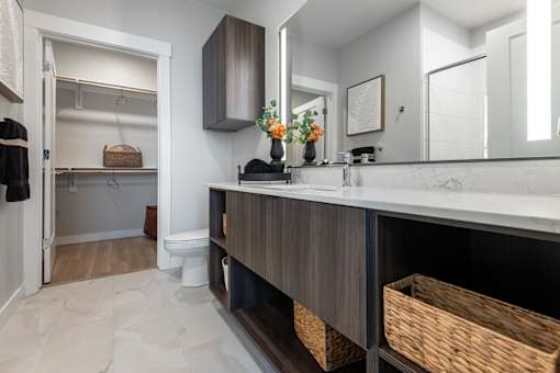 A bathroom with a white counter top and a mirror above it.