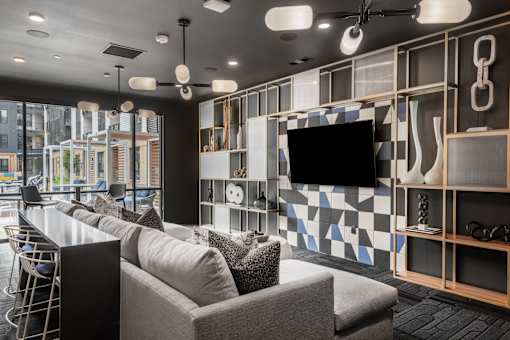 A modern living room with a grey sofa and a television mounted on the wall.