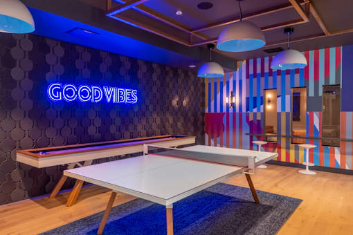 A room with a pool table and a neon sign that says "Good Vibes".