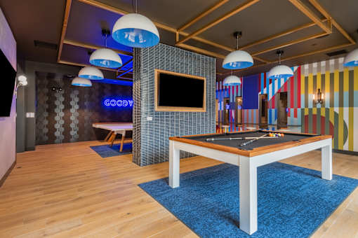 A room with a pool table and a TV mounted on the wall.