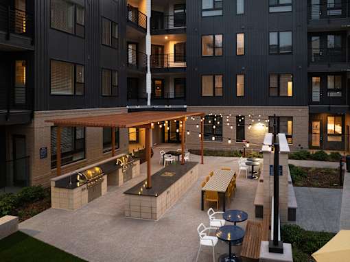 A patio area with tables and chairs is surrounded by apartment buildings.