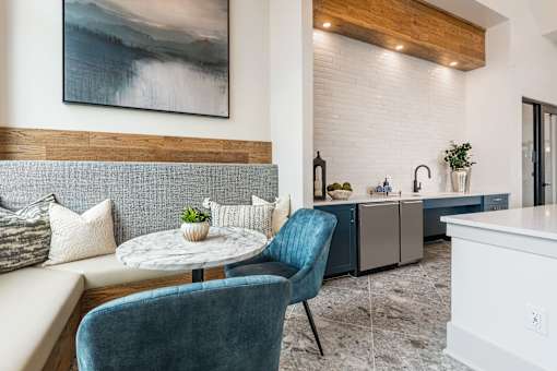 A blue chair sits in a modern kitchen with a white table and a painting on the wall.