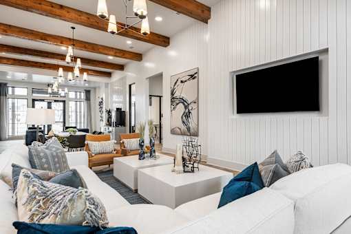 A living room with a white couch and a black TV mounted on the wall.