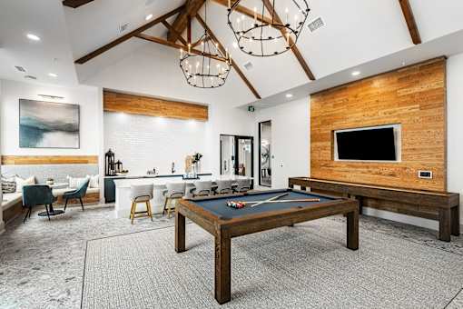 A billiard table is in the middle of a room with a wooden wall and a television.