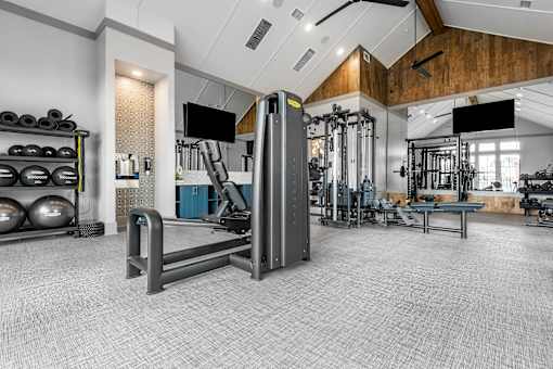 A gym with a variety of equipment including a squat rack, weight bench, and a flat screen TV.