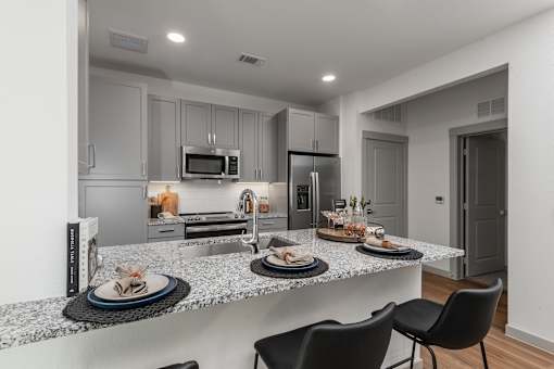 A modern kitchen with a dining table set for two.