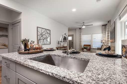 A modern kitchen with a granite countertop and stainless steel sink.