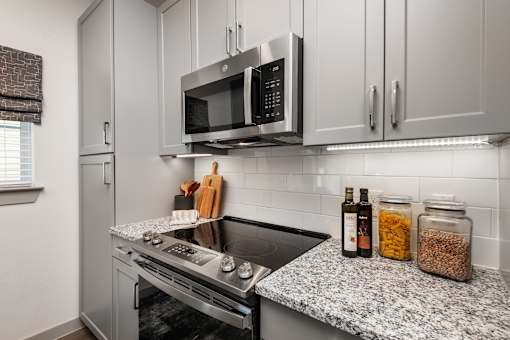 A modern kitchen with a stove top oven and microwave above it.