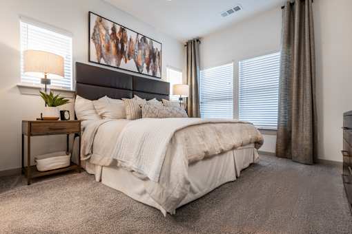 A bedroom with a large bed and a painting on the wall.