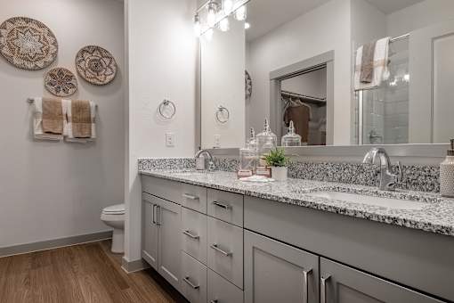 A bathroom with a marble countertop and a mirror above it.