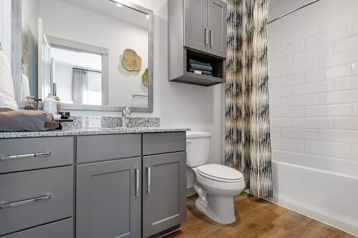 A bathroom with a toilet, sink, and a mirror.