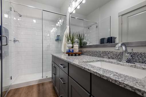 A bathroom with a marble countertop and a walk-in shower.