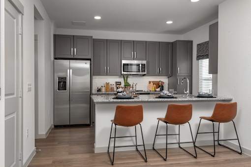 a kitchen with stainless steel appliances and a counter with three stools