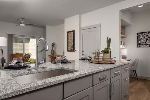 A modern kitchen with a marble countertop and a stainless steel faucet.