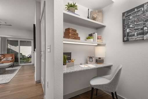 A modern home office with a desk, chair, and a plant.