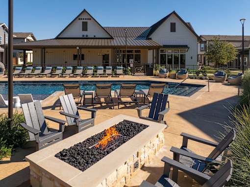 A pool area with a fire pit and lounge chairs.