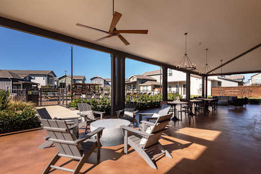 A patio with chairs and a table is covered by a white roof.
