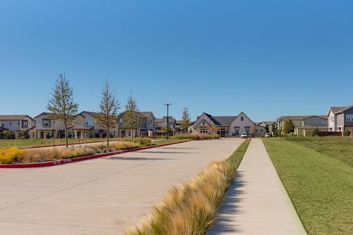 A row of houses with a sidewalk in front of them.