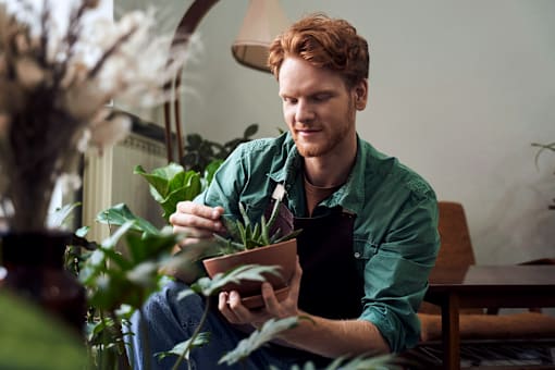 A man in a green shirt is sitting and reading a book.