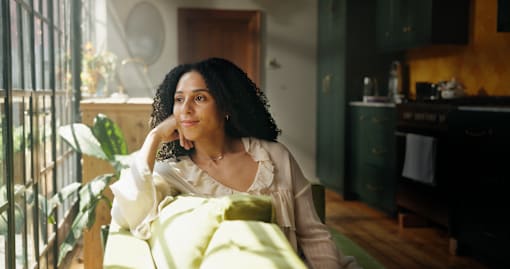 A woman in a white blouse is sitting on a green couch.