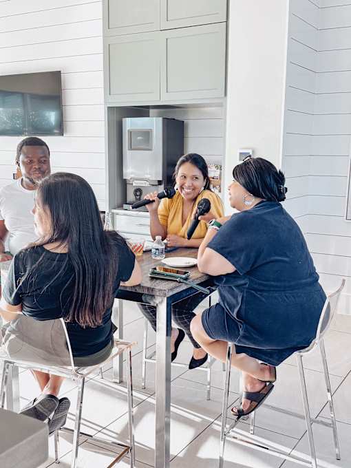 a group of people sitting around a kitchen table talking