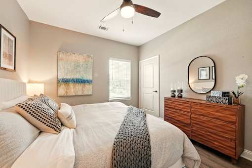 A bedroom with a bed, dresser, and a ceiling fan. at Beau Chene Lake Charles Apartments, Lake Charles, LA, 70605
