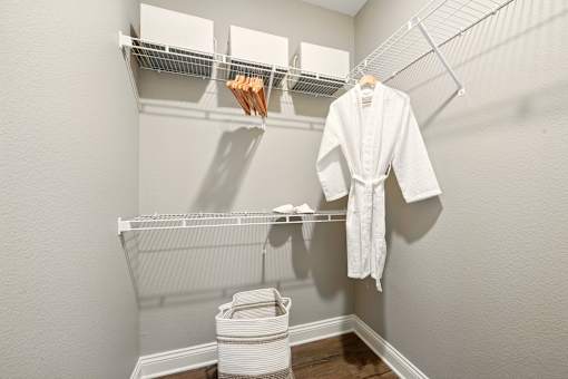 A white robe is hanging on a rack in a small, white bathroom. at Beau Chene Lake Charles Apartments, Lake Charles, Los Angeles