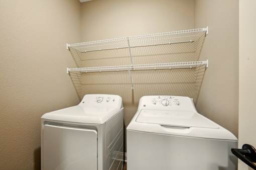 Two white front loading washing machines in a laundry room at Beau Chene Lake Charles Apartments, Lake Charles, Los Angeles