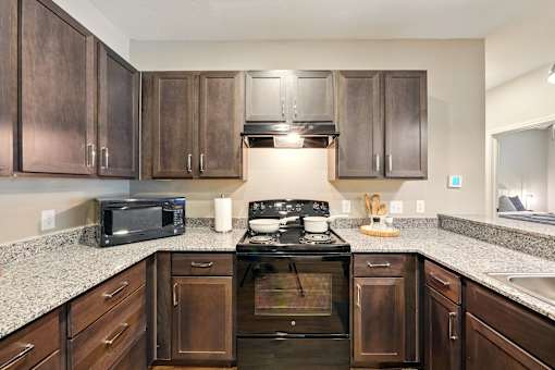 A kitchen with a stove top oven and microwave. at Beau Chene Lake Charles Apartments, Lake Charles, LA, 70605