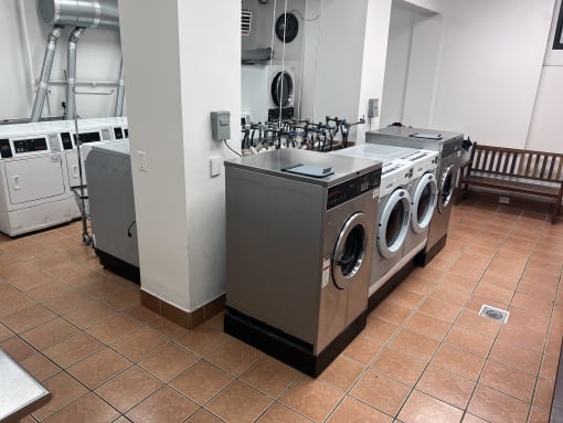 a row of washing machines and other appliances in a laundry room at Clinton Towers, New York, 10457