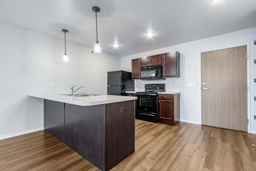 A kitchen with a white counter top and wooden floors.