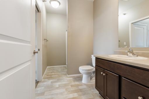 A bathroom with a toilet, sink, and mirror.