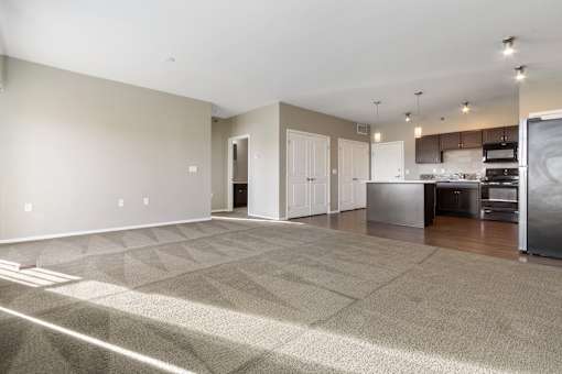 A spacious room with a kitchen area in the background.