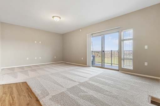 A spacious room with a large rug and sliding glass doors.