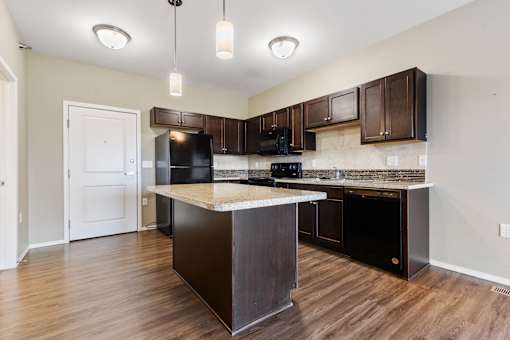 A kitchen with dark brown cabinets and black appliances.