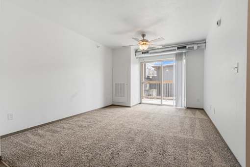 A room with a carpet floor and a ceiling fan.
