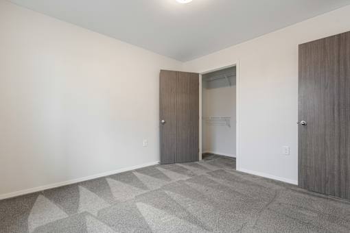 A room with a carpeted floor and two doors.