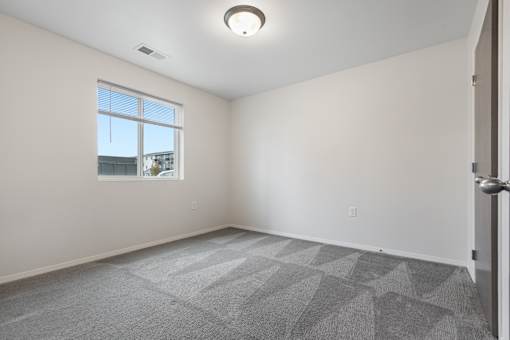 A room with a carpeted floor and a window.