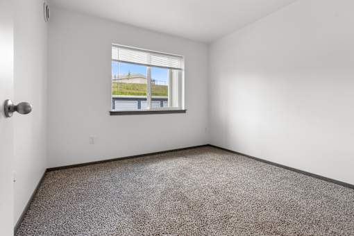 Empty room with a window overlooking a building.