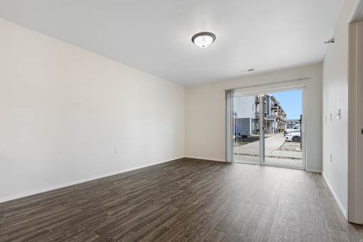 A room with a wooden floor and a sliding glass door leading to a balcony.