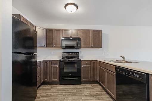 A kitchen with a black fridge, black oven, and black stove top.