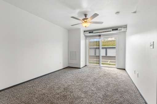 A room with a ceiling fan and carpeted floor.
