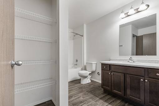 A bathroom with a toilet, sink, and wooden floors.