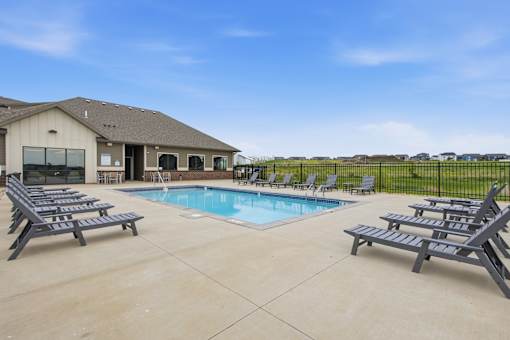 A pool with a house and a fence in the background.
